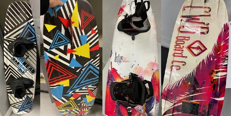 Two wakeboards: One wakeboard is white, blue and black and the second is white with red, purple and pink feathers.