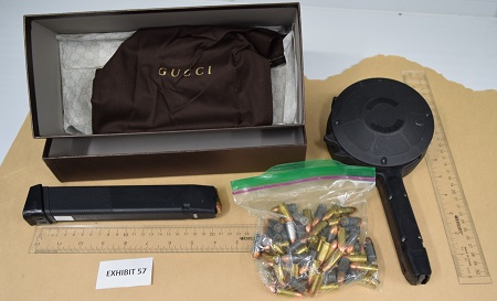 1 handgun magazines, 1 drum magazine. A box with a with a Gucci bag in it. 2 rulers showing the size of the magazines and a zip lock bag full of ammunition.