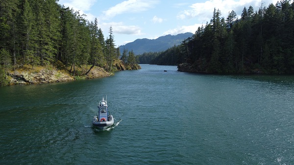 Le gendarme Kyle Toole est à la barre du Zodiac de la GRC en Colombie Britannique dans les eaux bleues du lac Harrison, près de l’île Sheers et du site de camping Ten Mile Bay. 