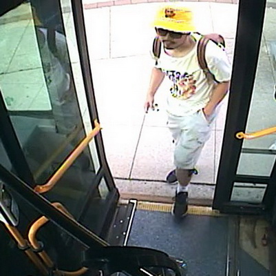 Photo of Ryan Liu getting on a bus, wearing green shorts, a white t-shirt, black shoes and a yellow hat