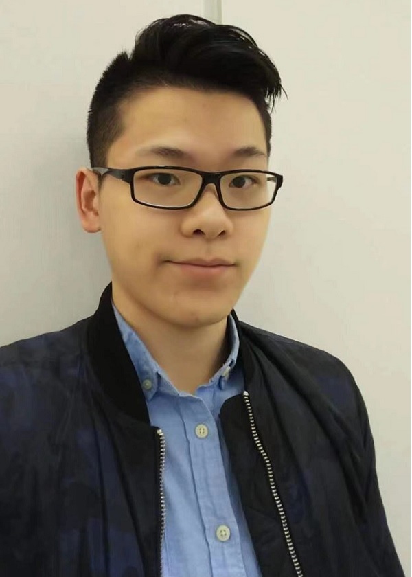Young Asian man with black hair, brown eyes, wearing black rimmed glasses, a black zip up jacket and a blue button up dress shirt. The man has a white background behind him.