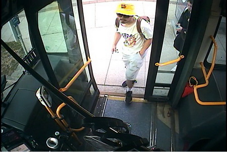 Photo of Ryan Liu getting on a bus, wearing beige shorts, a white t-shirt, black shoes and a yellow hat