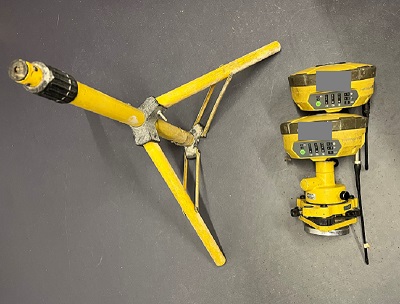 Yellow and black tripod stand with two survey head pieces with key information greyed out.