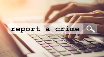 hands typing 'report a crime' on a keyboard
